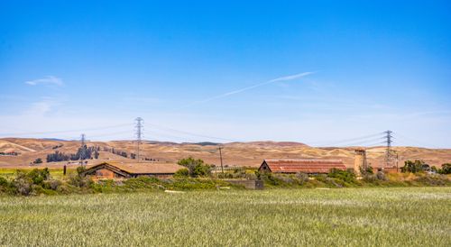 Free Idyllic rural scene of a serene field with hills in the background under a clear blue sky. Stock Photo