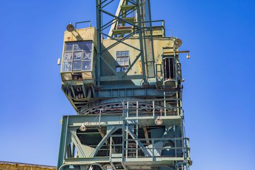 Free A large industrial crane made of iron and steel set against a clear blue sky. Stock Photo