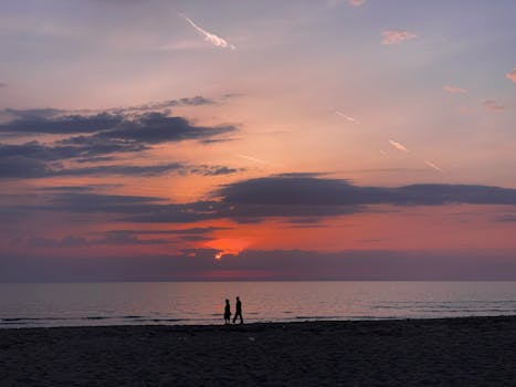 Silhouette of couple walking by the sea during a stunning sunset in Albania.