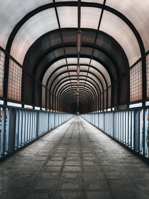 Free Long covered pedestrian tunnel with symmetrical arches creating a vanishing point perspective. Stock Photo