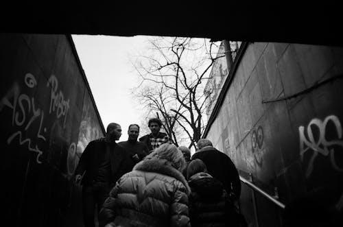 Фотография людей, идущих между бетонной стеной в оттенках серого