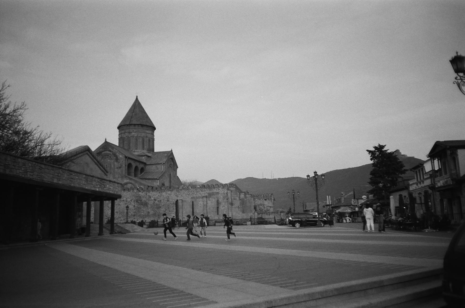 Grayscale Photo of People Between Buildings