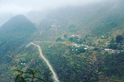 Free Aerial view of a winding road through lush mountainous countryside under cloudy skies. Stock Photo