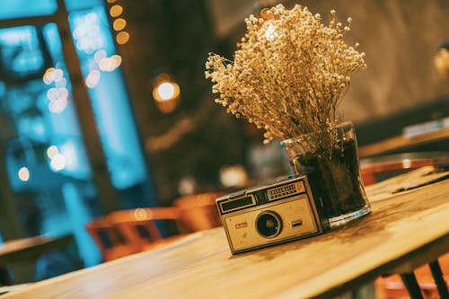 Fotocamera Slr Grigia E Nera Vicino Al Vaso Di Vetro Trasparente