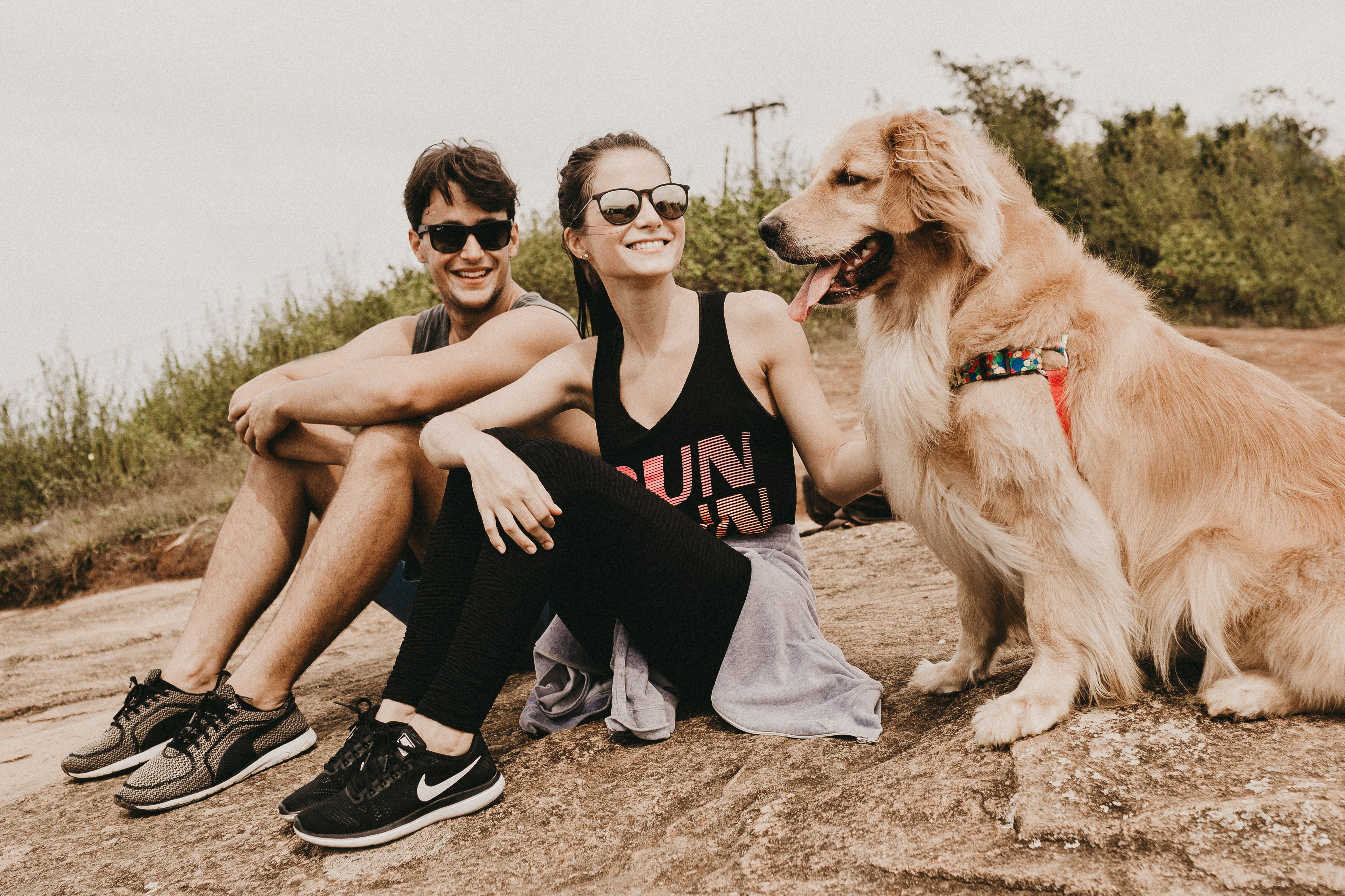 Man and Woman Sitting on the Ground Near a Brown Dog · Free Stock Photo