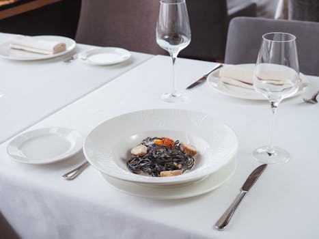 Beautifully plated squid ink pasta on a fine dining table setting, ready to serve.