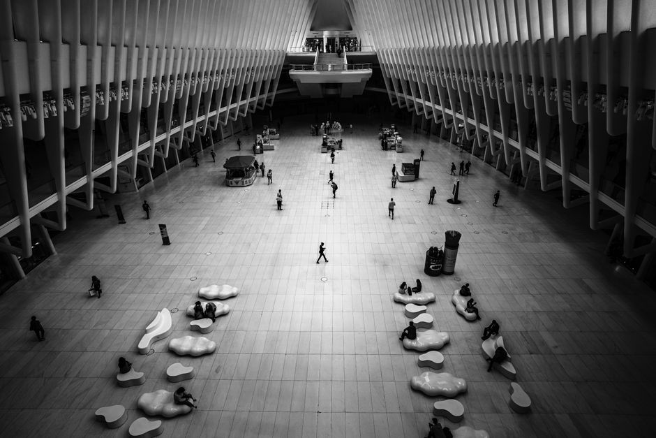 Black and white spacious corridor with modern architecture and people interacting.