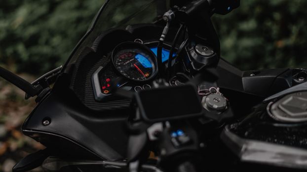 Detailed shot of a motorcycle dashboard, highlighting the instrument cluster and handlebar controls.
