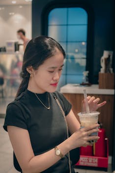 A woman in casual attire enjoys bubble tea in a modern cafe. Lifestyle and leisure concept.
