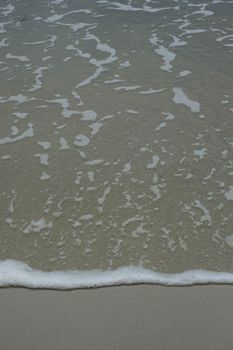 A serene view of ocean waves gently touching the sandy shore, perfect for relaxation themes.
