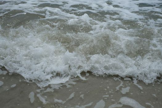 Close-up of gentle ocean waves crashing onto a sandy beach, capturing the essence of nature's beauty.