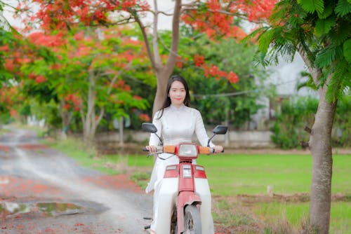 A Woman in an Ao Dai Riding a Scooter