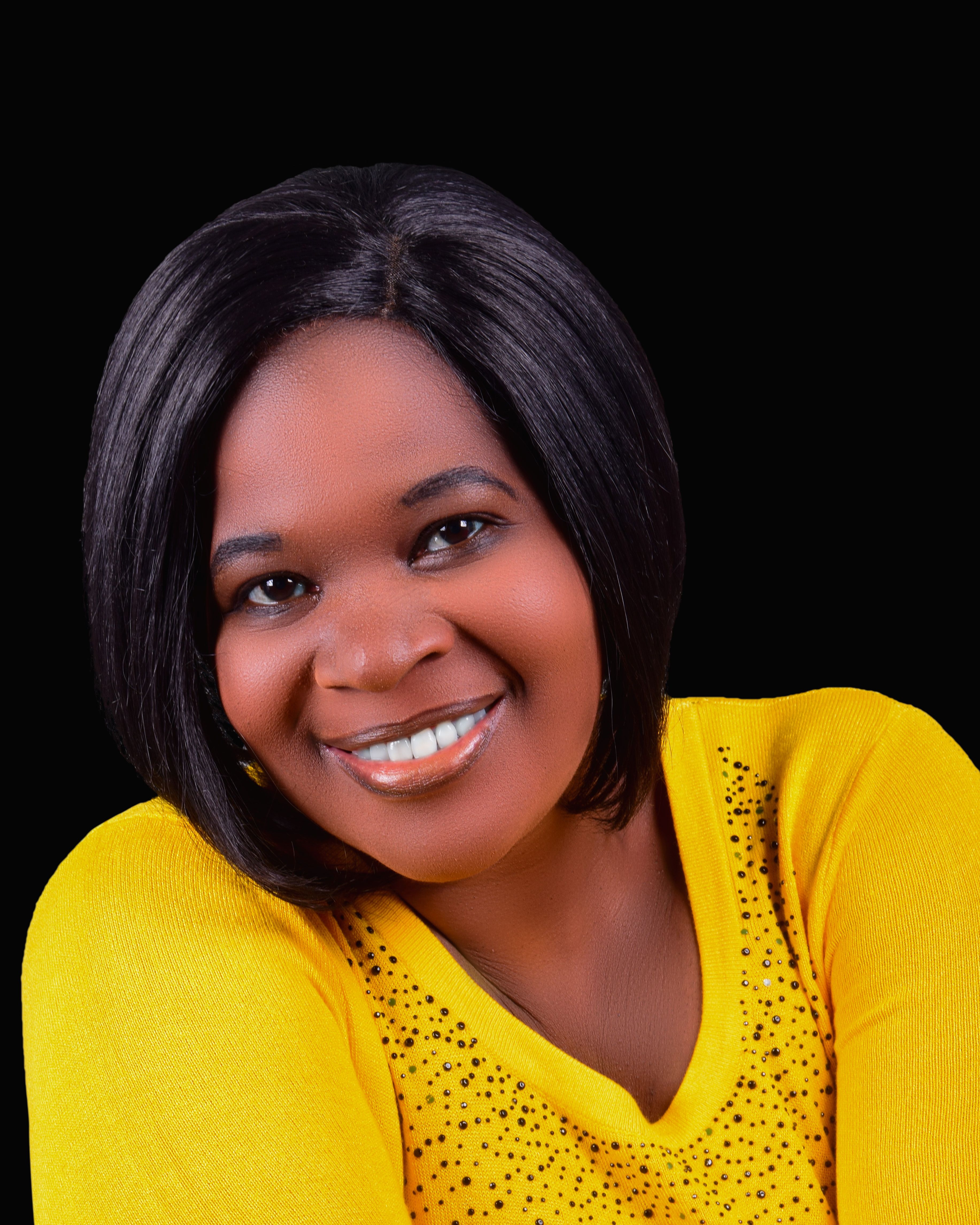 Portrait of a joyous woman in a vibrant yellow top against a black background, exuding happiness.