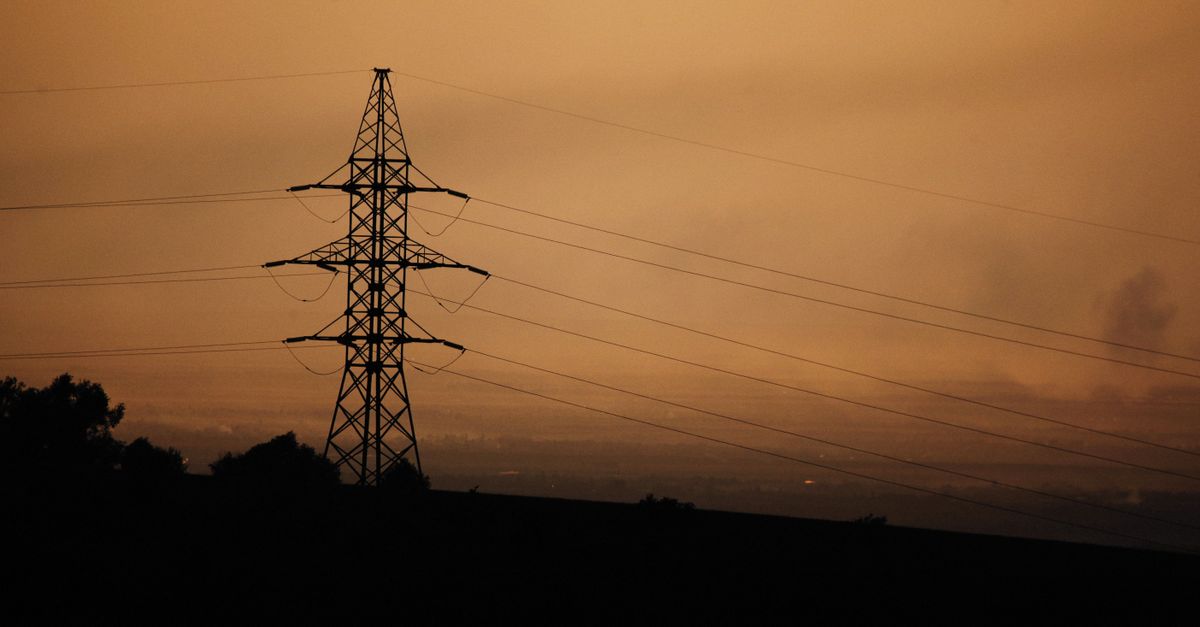 Silhouette eines Hochspannungsmastes vor einem warmen Abendhimmel, Symbol fĂĽr die Energieversorgung.
