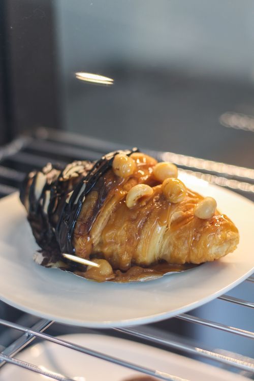 Free Indulge in a tantalizing chocolate and caramel topped croissant with nuts. Stock Photo
