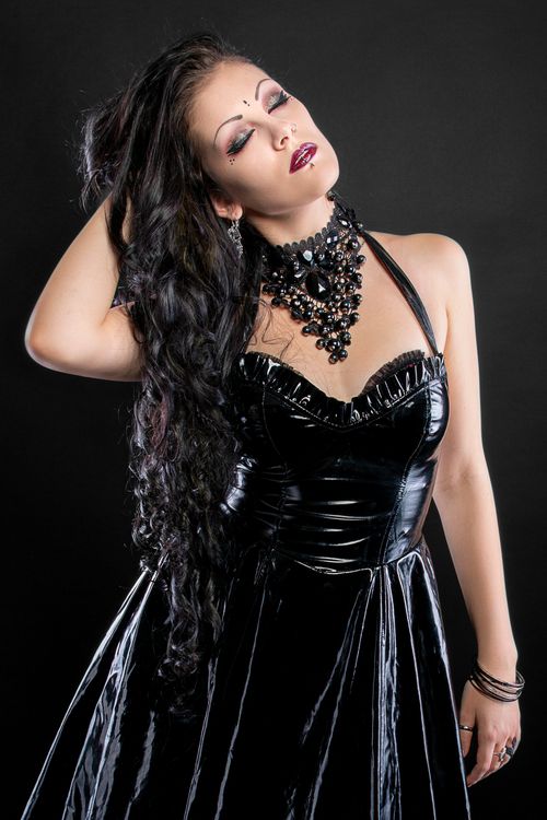 Free Stunning fashion portrait of a woman in a black leather dress with dramatic accessories in a studio setting. Stock Photo