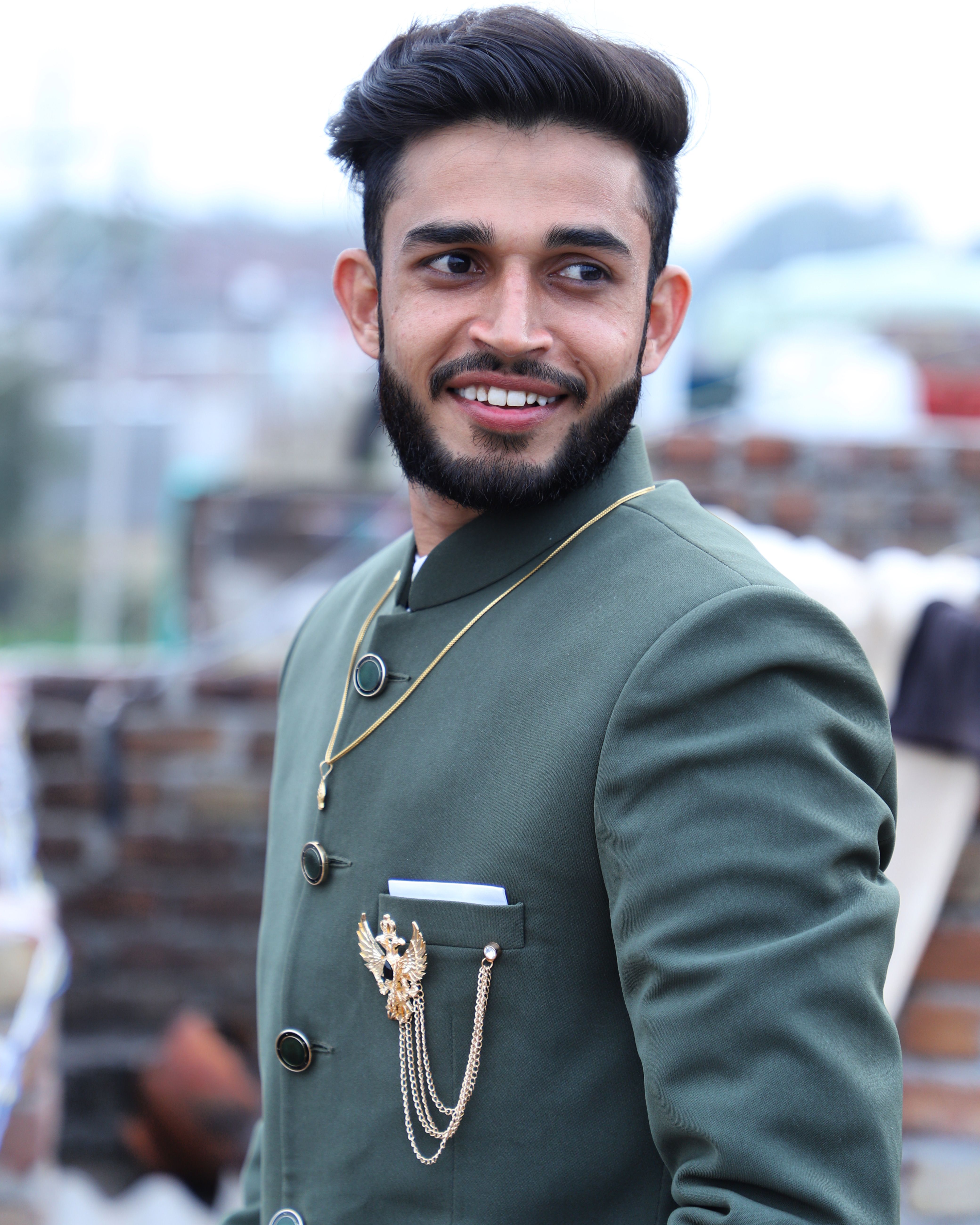 Portrait of a bearded South Asian man wearing traditional attire in an outdoor setting, exuding elegance and style.