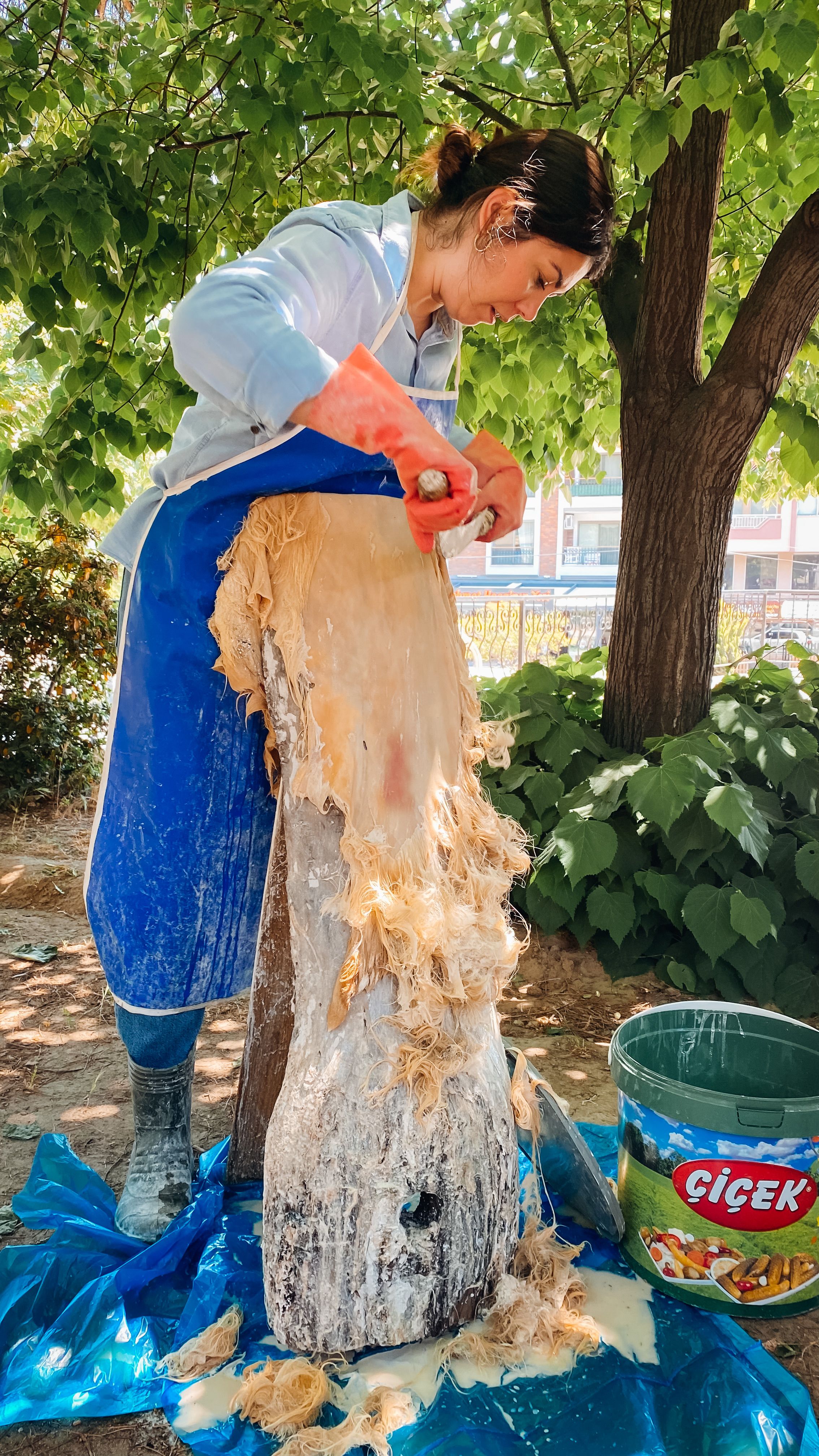 Woman skillfully scraping material from wood outdoors in Bergama, Turkey.