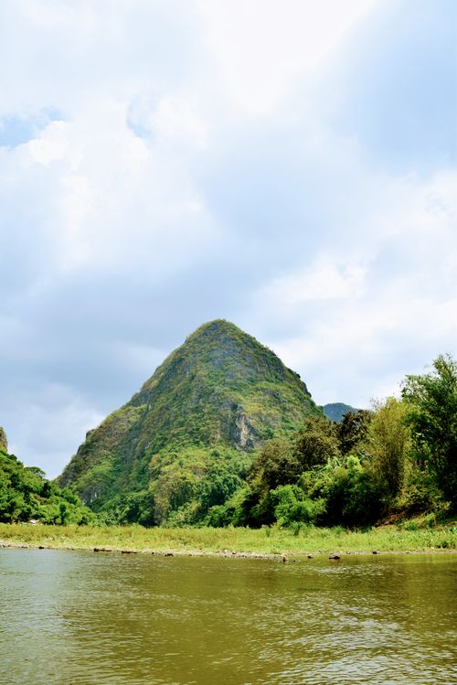 Free Picturesque mountain landscape with lush greenery and river under a cloudy sky. Stock Photo