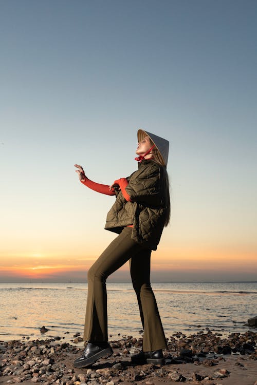 Free Woman in Black Coat Standing on Beach during Sunset Stock Photo