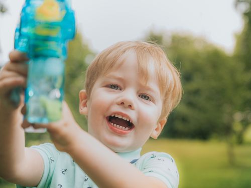 Free Happy blond child playing outside with a blue toy on a sunny day. Stock Photo