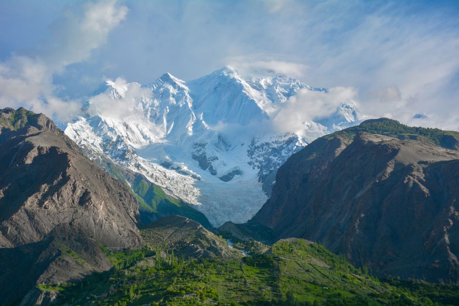 Snow-covered peaks of the Hindu Kush in Gilgit-Baltistan under a clear blue sky.