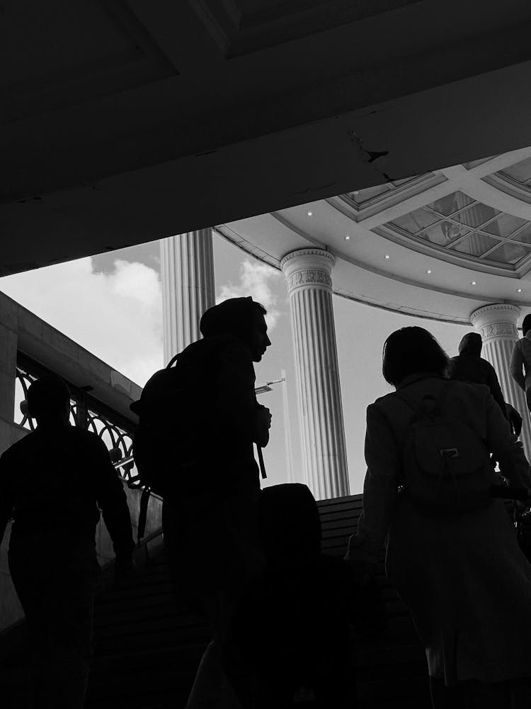 Grayscale Photo Of People Going Up The Stairs