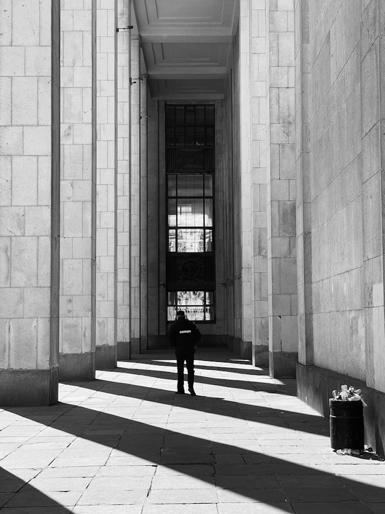 Black And White Photo Of Security Guard In Column Shade