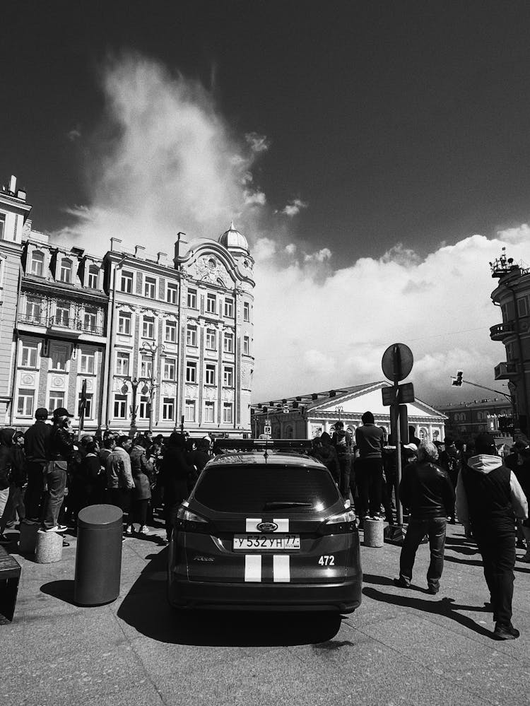 Grayscale Photo Of A Car On The Street With The People