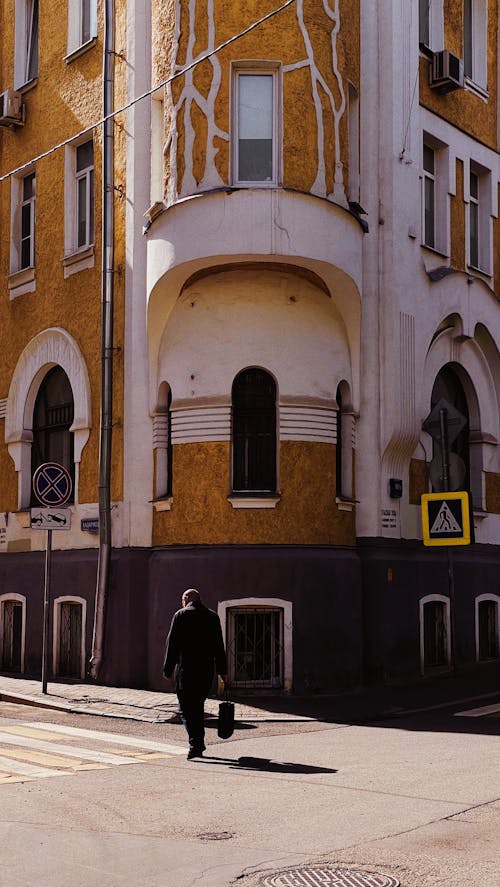 Man Walking near the Corner Building