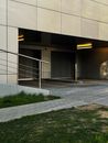Contemporary building exterior with concrete ramp and metal railing.
