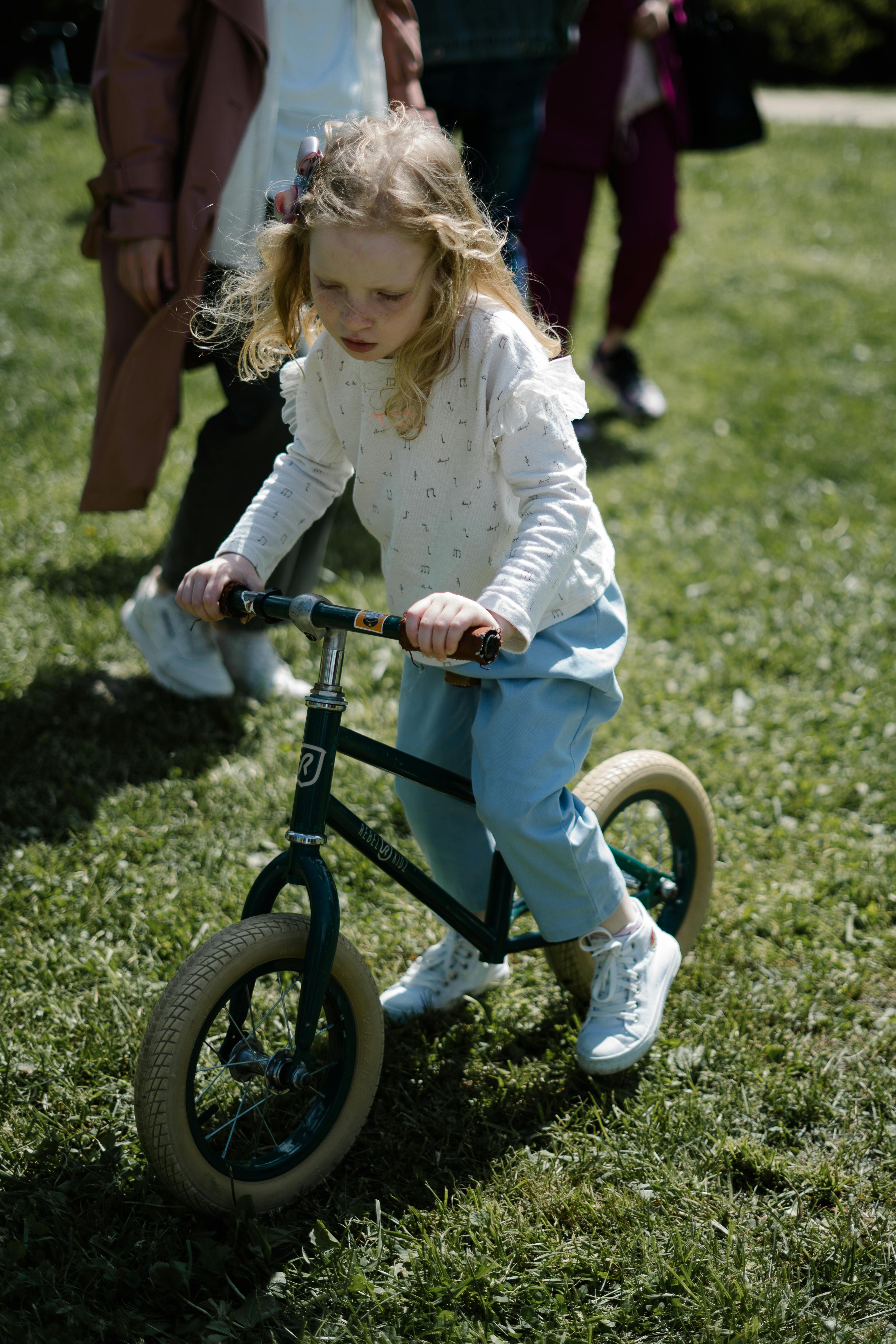 A young girl enjoys riding a bicycle on a sunny day in the park.