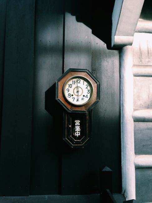 Antique wall clock on a dark wooden facade of a traditional Japanese building in Nagano, Japan.