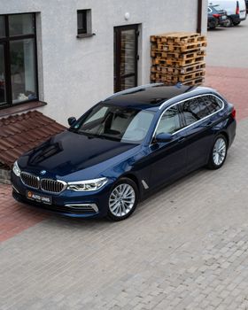 A sleek navy blue car is parked outside an urban building, showcasing modern design.