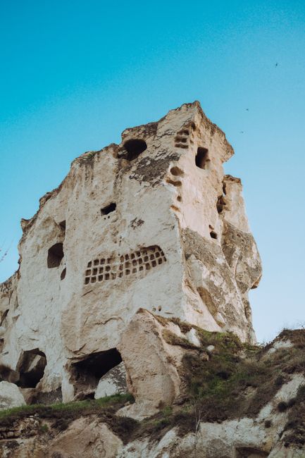 Explore the ancient rock formations and ruins of Cappadocia under a clear sky in T眉rkiye.