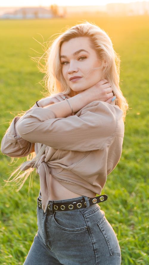 Free Elegant portrait of a young woman posing confidently in a sunlit field. Stock Photo