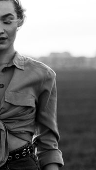 Artistic black and white portrait of a woman in a crop top outdoors, conveying elegance.
