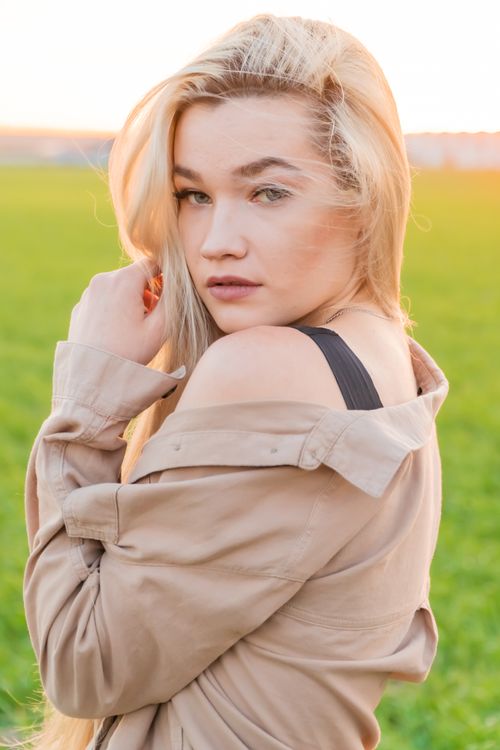 Free A woman with blond hair posing in an open field at sunset, exuding elegance and tranquility. Stock Photo