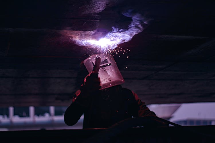 Man In Protective Gear Welding In Dark