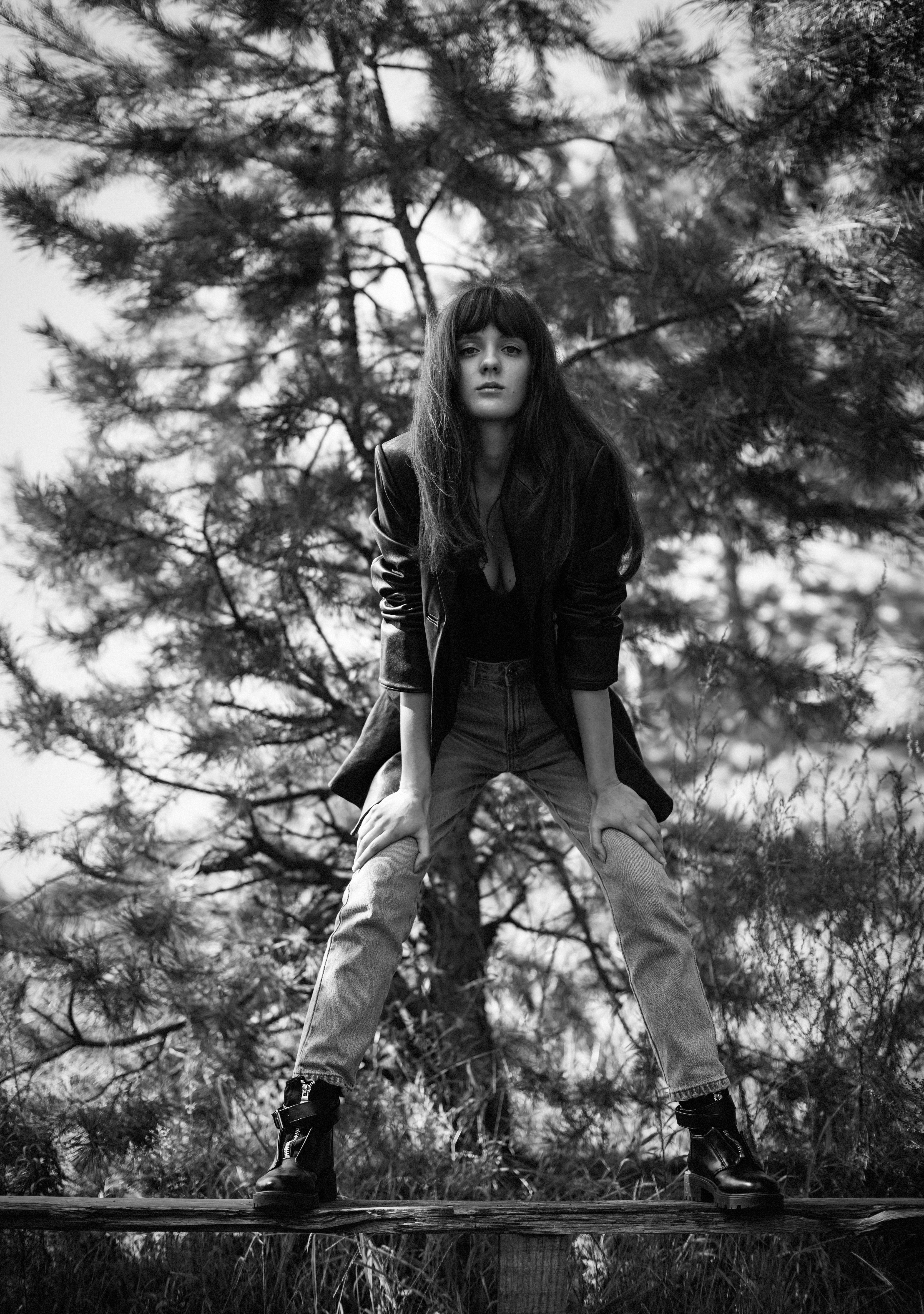 Black and white portrait of a young woman in a leather jacket posing outdoors.