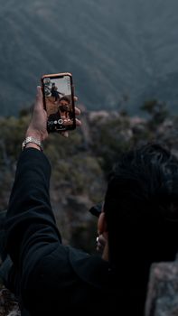 A person taking a selfie outdoors in the scenic Aseer Mountains, Saudi Arabia.