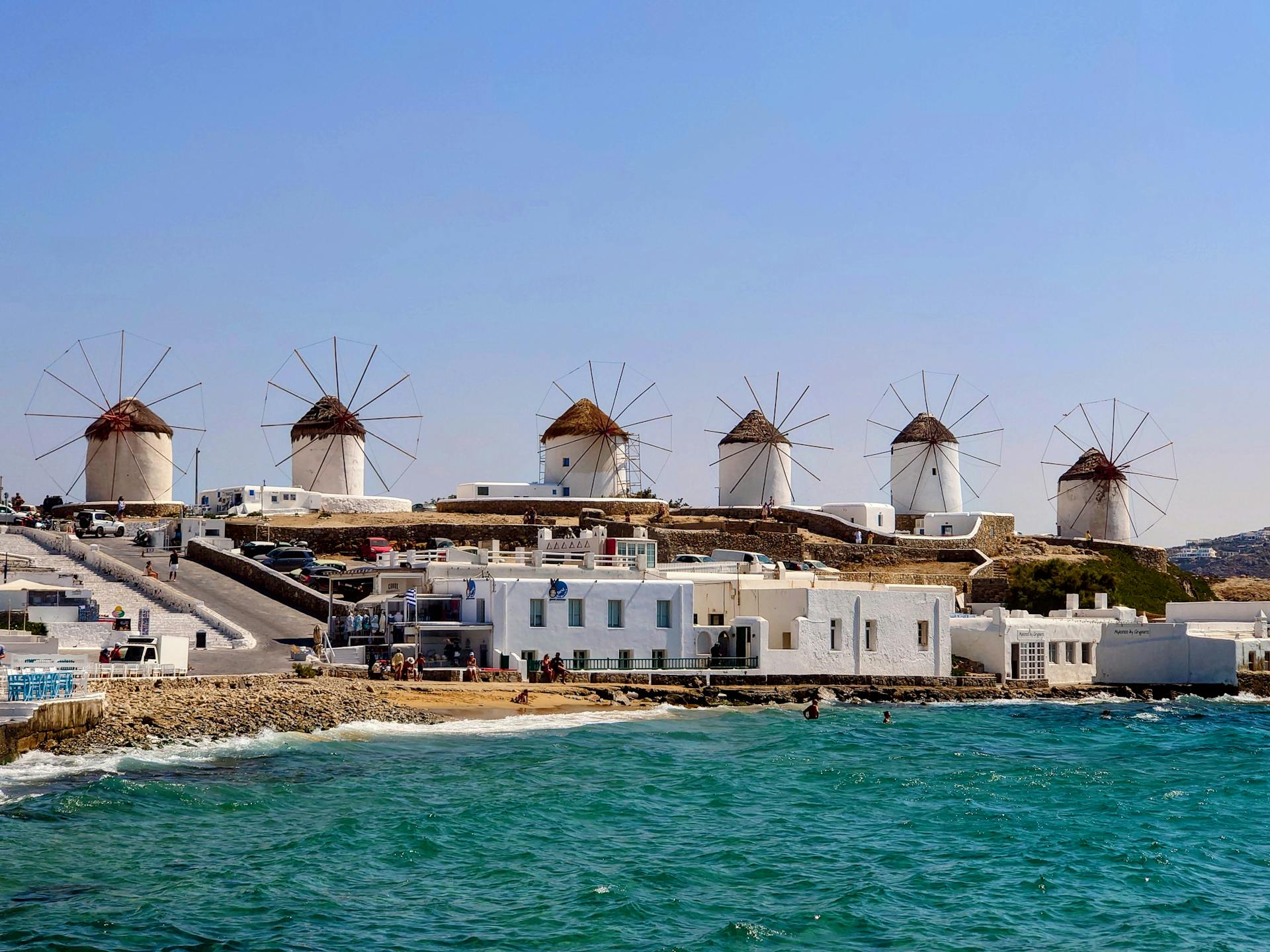 A scenic view of the historic Mykonos windmills against the azure Aegean Sea.
