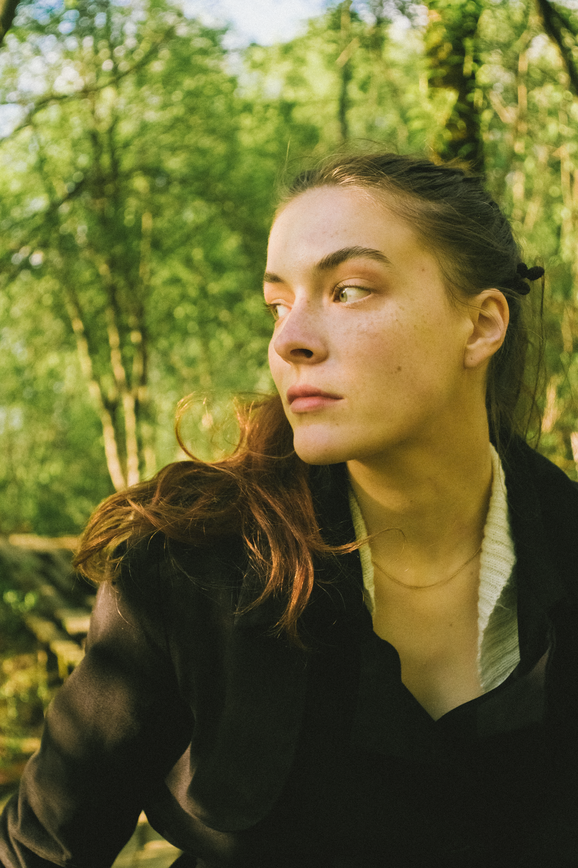 A Woman in Black Sweater Standing Near Green Trees · Free Stock Photo