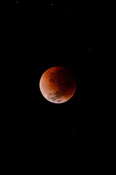 Capture of a blood moon during a lunar eclipse, set against a starry night sky.