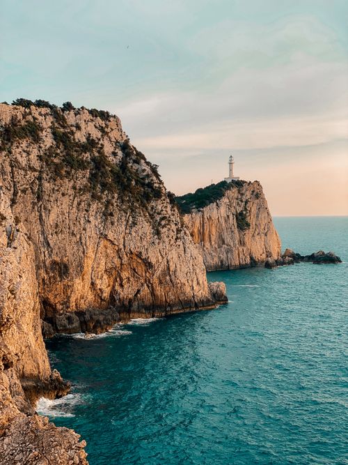 Free Stunning cliffside view of the lighthouse on Lefkada island in Greece during dusk with azure sea. Stock Photo