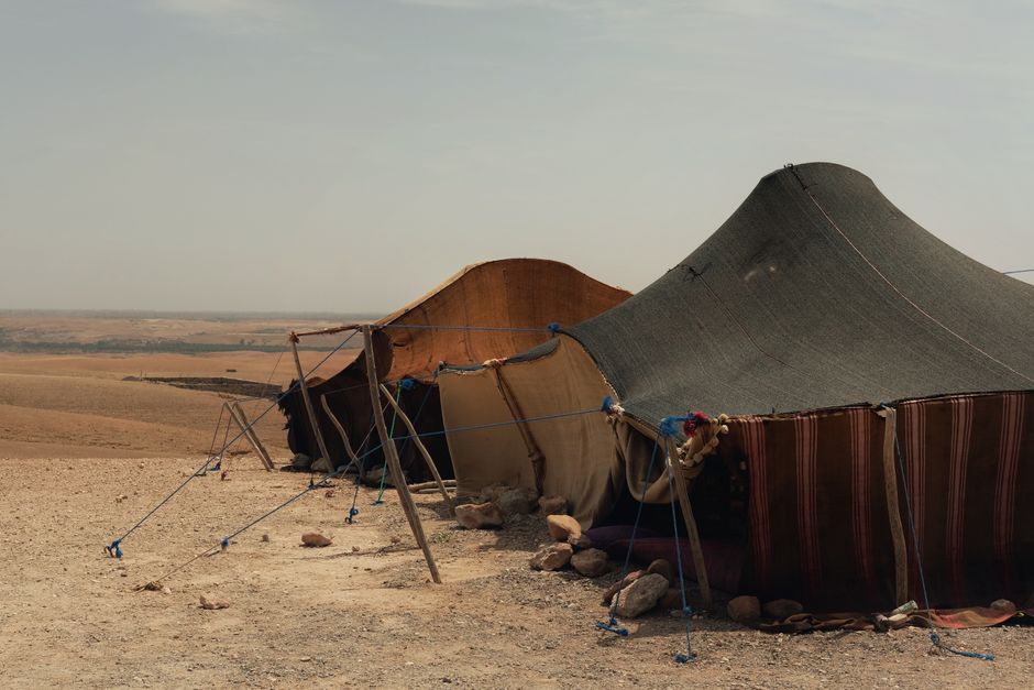 A serene desert scene with traditional Bedouin tents under a clear sky, showcasing nomadic lifestyle.