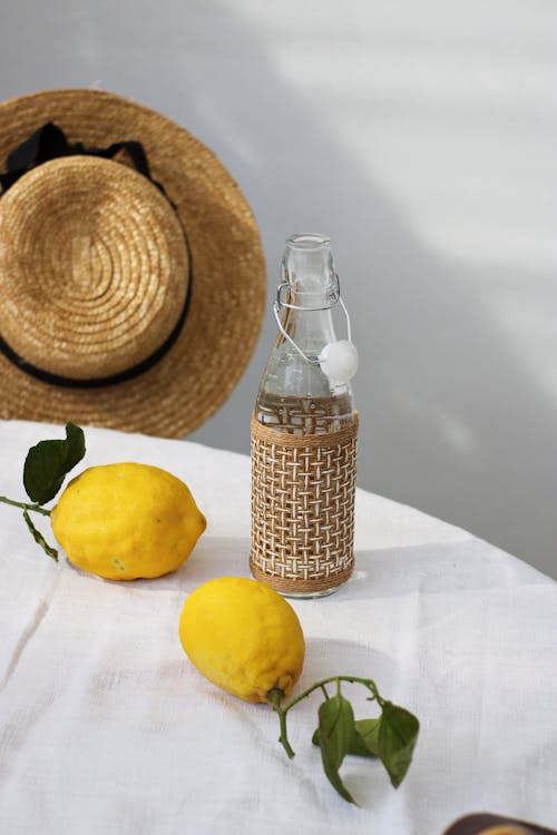 Бесплатное стоковое фото с вертикальный выстрел, лимоны, прозрачная бутылка