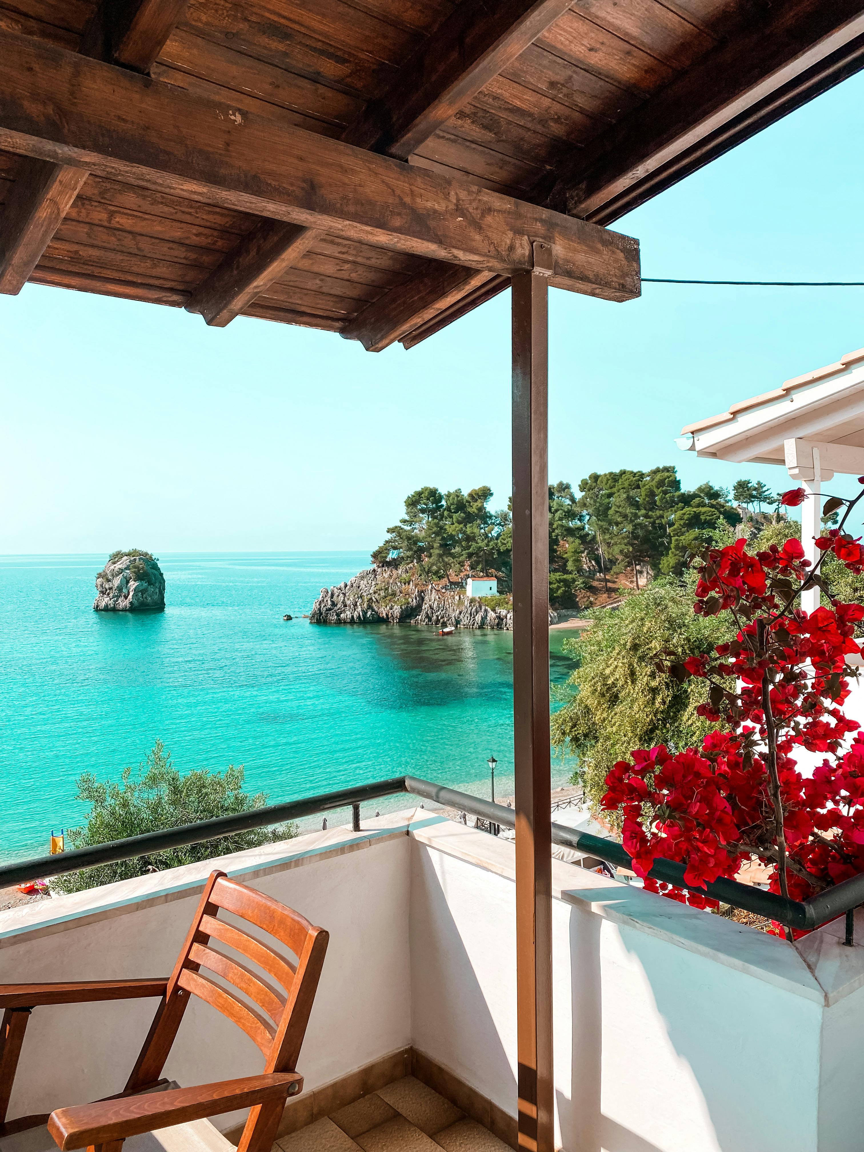 Breathtaking view of the ocean from a balcony in Greece, featuring vibrant flowers and coastal charm.