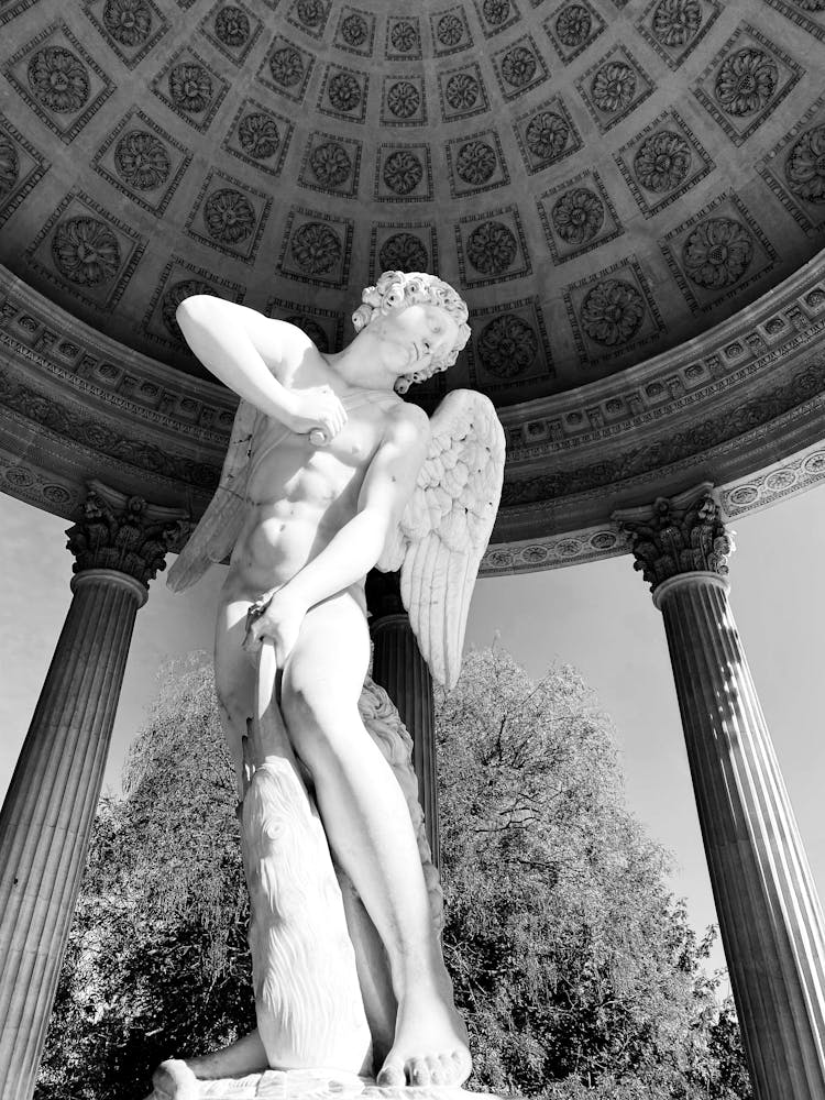 Grayscale Photo Of A Cupid Statue