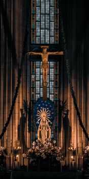Interior of a cathedral in Istanbul featuring a cross and Virgin Mary statue, illuminated by stained glass light.